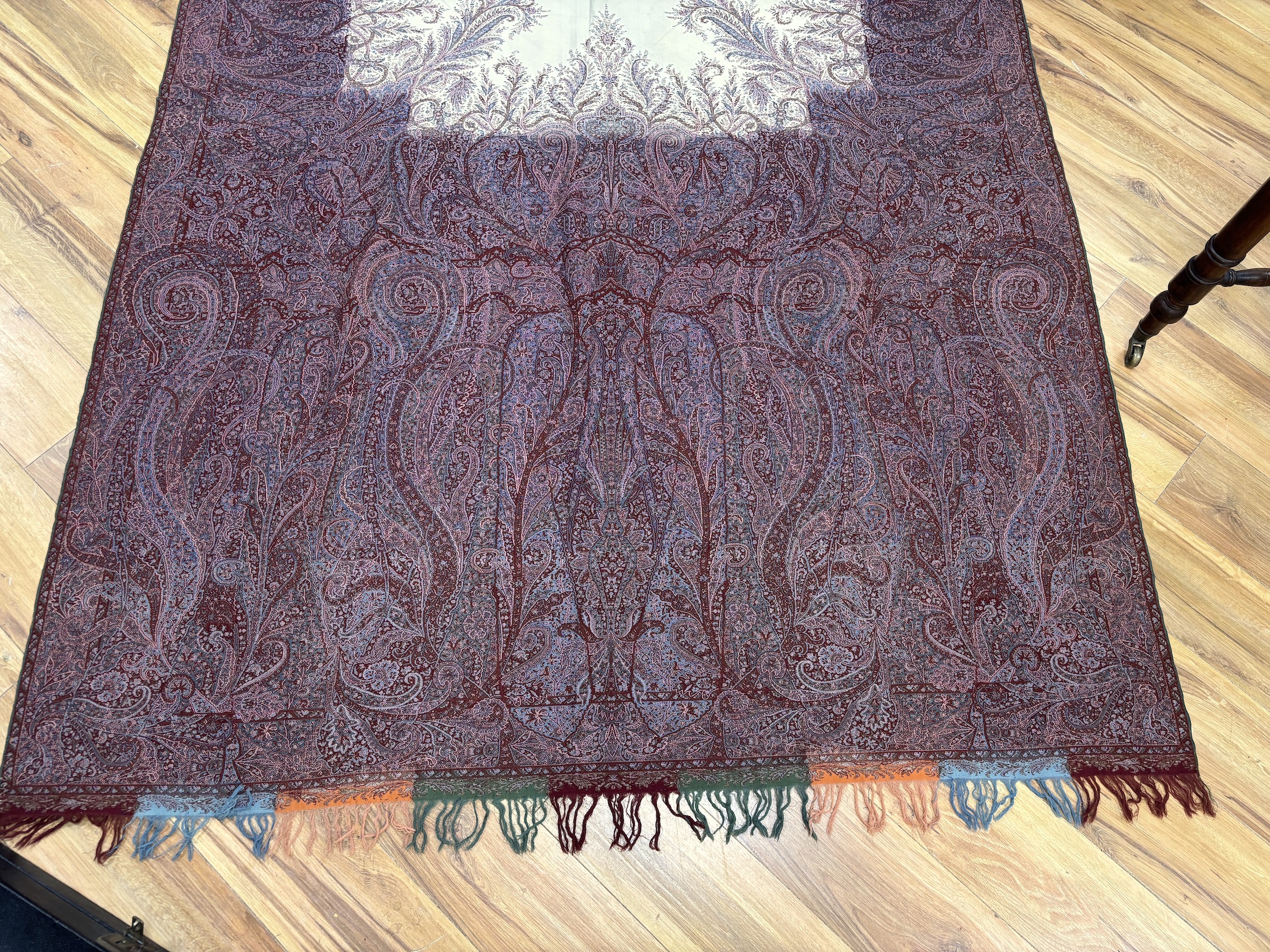 A late 19th century wool woven Paisley shawl with cream central cartouche (some damage)